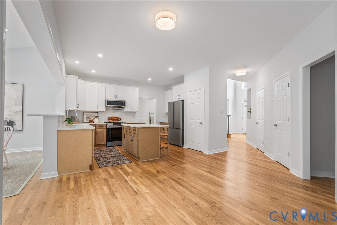 3929 Meadowview Lane, Richmond, VA 23223 Hardwood flooring throughout, white upper cabinetry, stainless steel appliances, kitchen island with seating, and recessed lighting