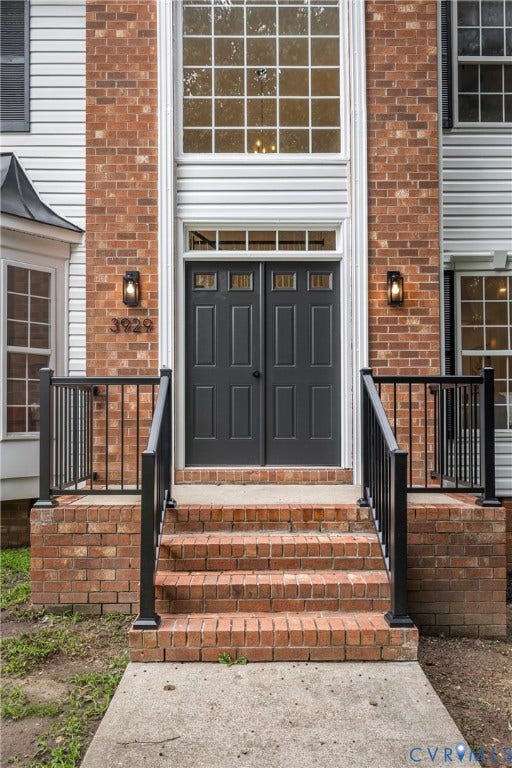 3929 Meadowview Lane, Richmond, VA 23223 Classic brick and white clapboard facade with a centered black six-panel entry door flanked by decorative lantern sconces