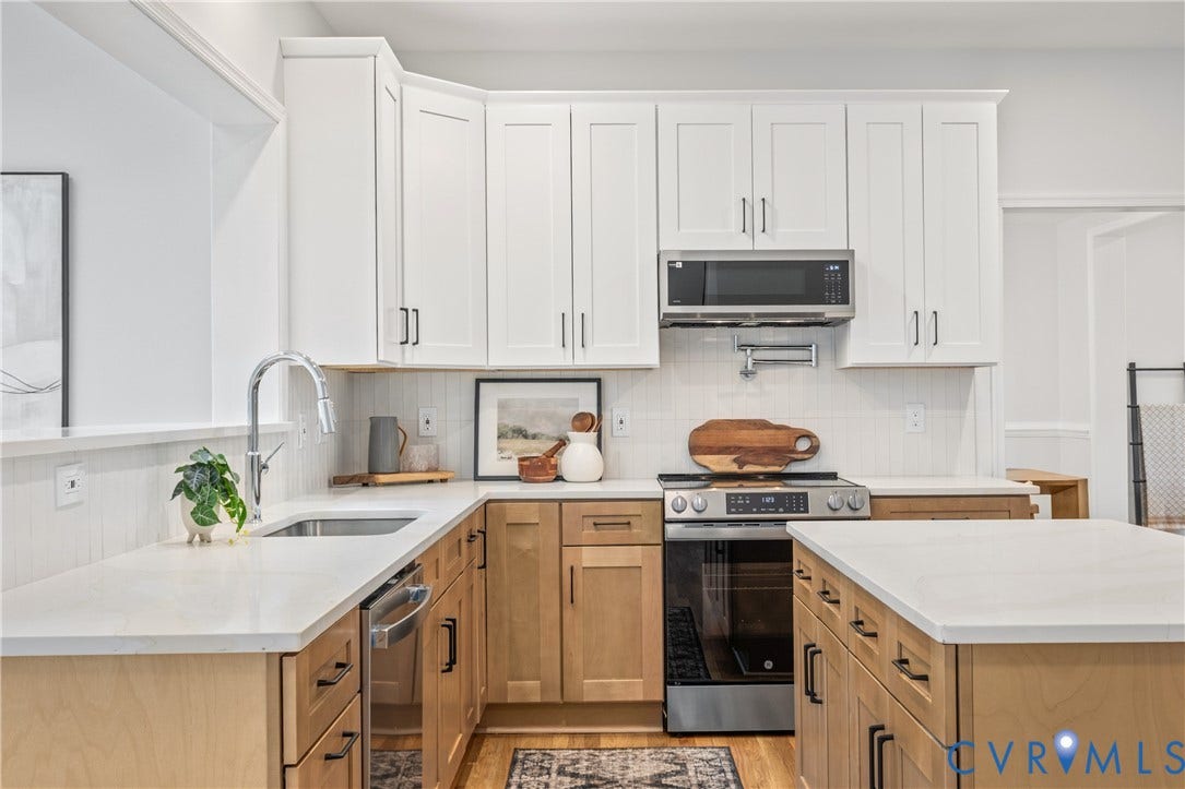 3929 Meadowview Lane, Richmond, VA 23223 Modern kitchen featuring white shaker-style cabinetry with brushed nickel hardware, wood-finish lower cabinets, and a quartz countertop island