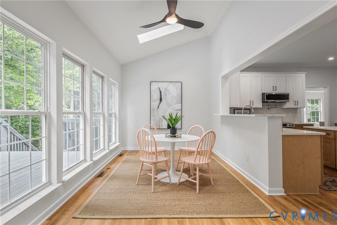 3929 Meadowview Lane, Richmond, VA 23223 Vaulted ceiling with a skylight, wood-finish flooring, multiple pane windows, and an open concept kitchen with white cabinetry and stainless steel appliances