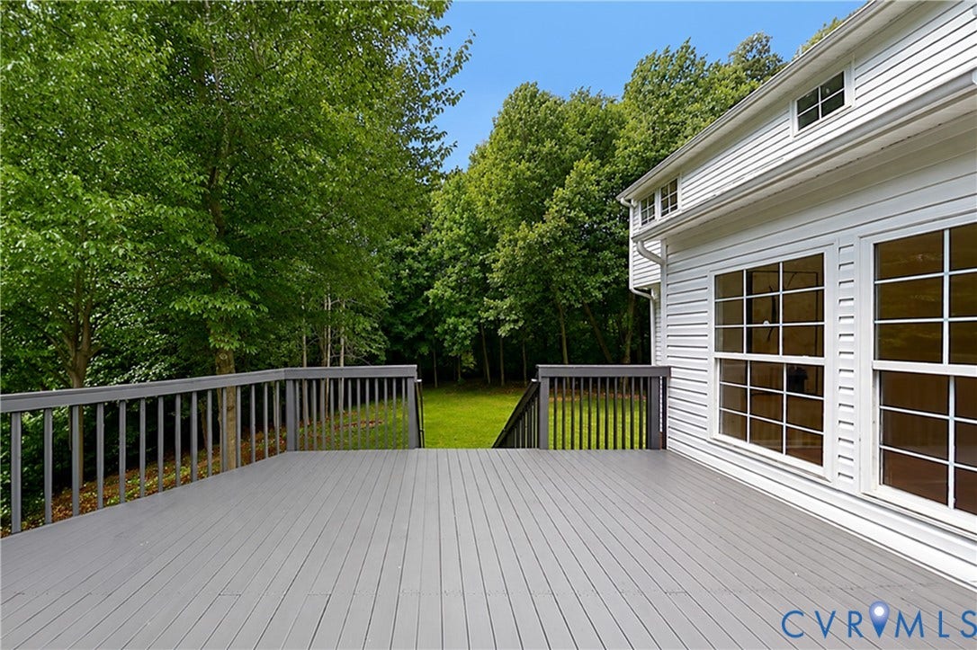 3929 Meadowview Lane, Richmond, VA 23223 Expansive grey composite decking with matching railings, set against a backdrop of mature trees, featuring large windows with white grid patterns, and white horizontal siding