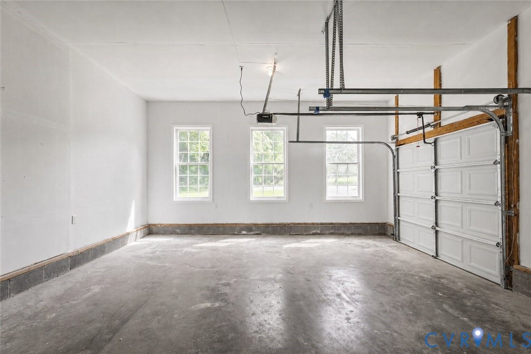 3929 Meadowview Lane, Richmond, VA 23223 Spacious garage featuring concrete flooring, three windows with grid panes, and a paneled garage door