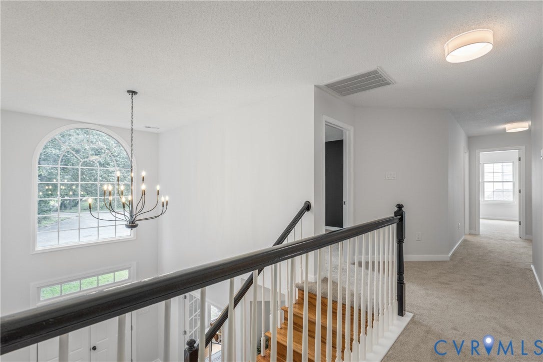 3929 Meadowview Lane, Richmond, VA 23223 Arched window, chandelier, wood stairs, carpeted hallway, black and white staircase railing