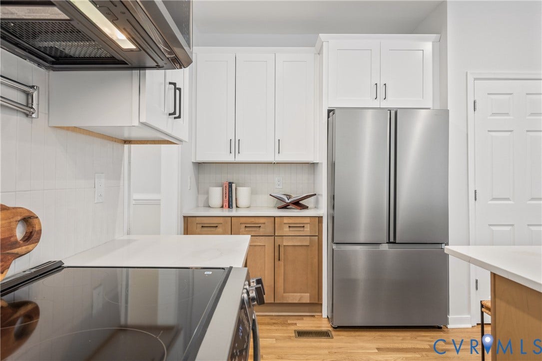 3929 Meadowview Lane, Richmond, VA 23223 Modern kitchen featuring stainless steel French-door refrigerator, white shaker-style cabinetry with chrome hardware, wood-finish flooring, quartz countertops, and stainless steel appliances including a professional-grade range hood