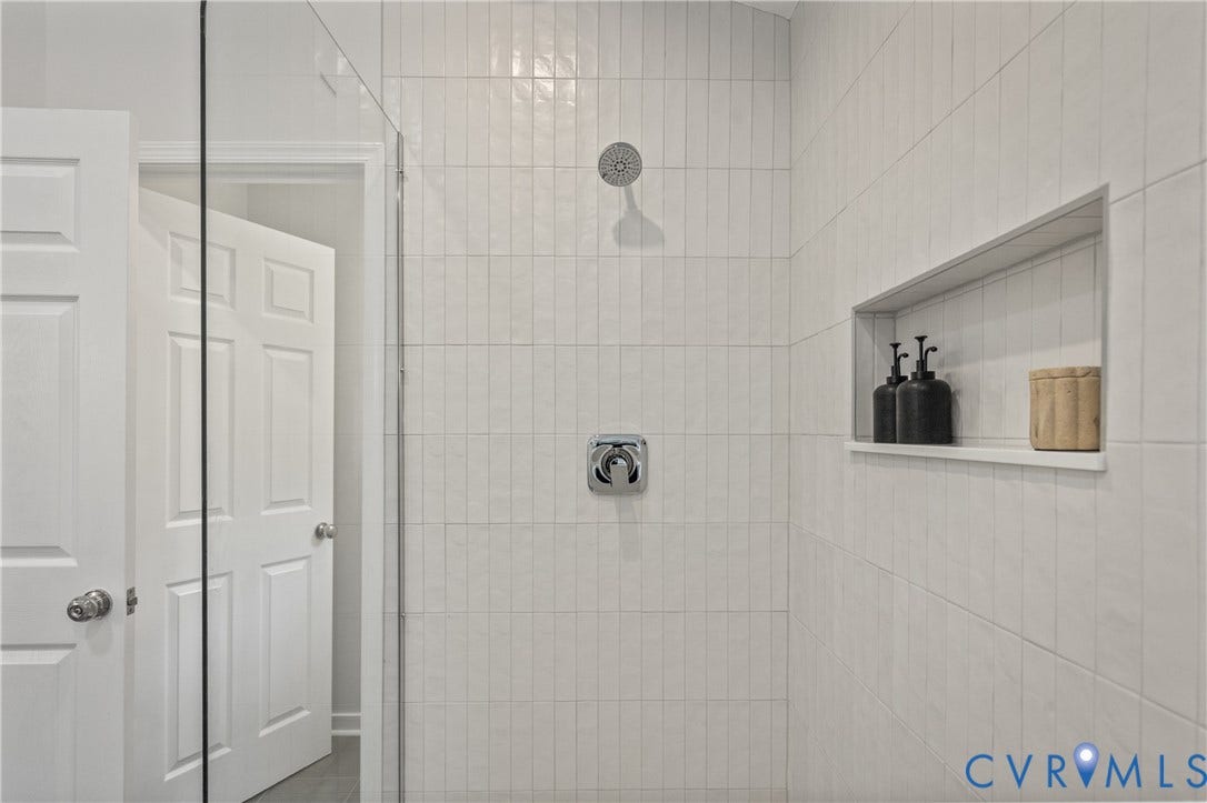 3929 Meadowview Lane, Richmond, VA 23223 Shower enclosure featuring a rain showerhead, chrome fixtures, floor-to-ceiling vertical tile, and a recessed niche