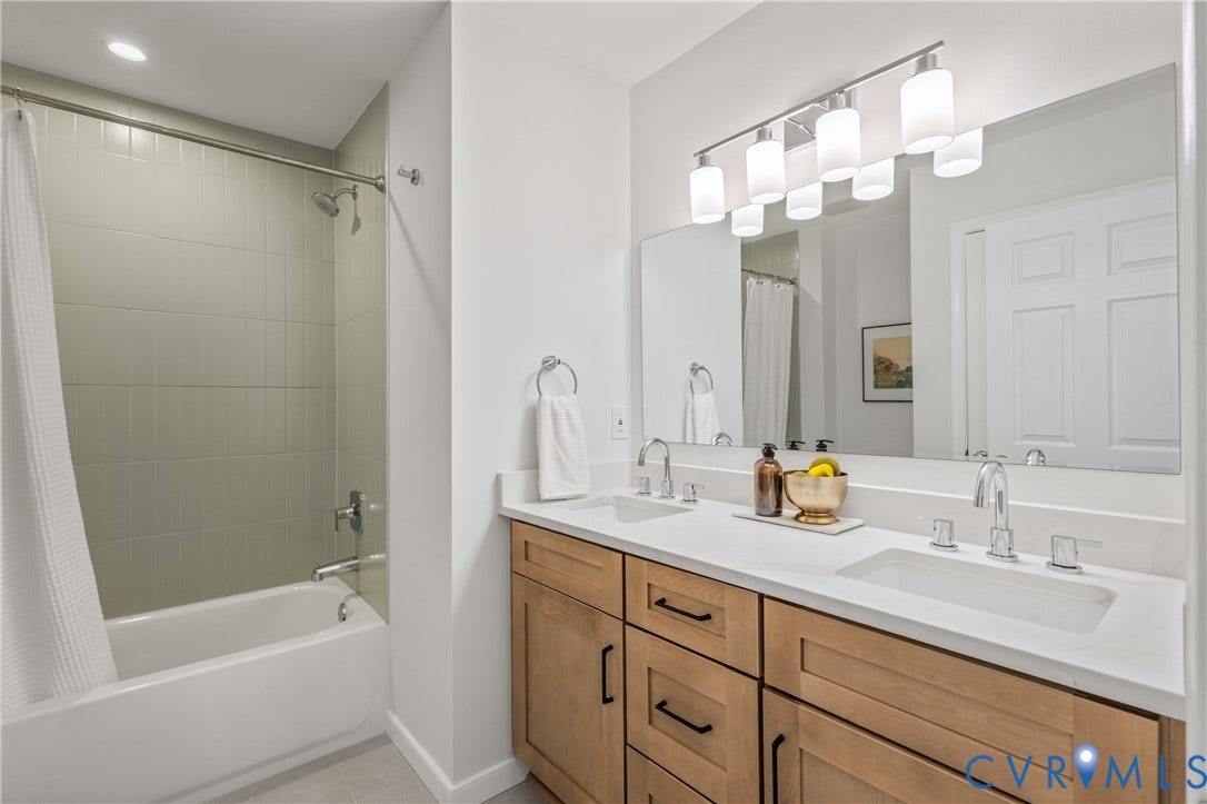 3929 Meadowview Lane, Richmond, VA 23223 Dual vanity with integrated sinks, light wood-finish cabinetry, and a full-width mirror