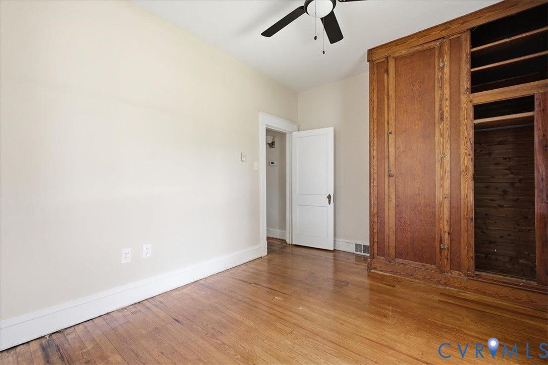 7232 Hopkins Road, North Chesterfield, VA 23237 Spacious bedroom featuring hardwood flooring, ceiling fan with integrated lighting, and custom wood-finish built-in cabinetry