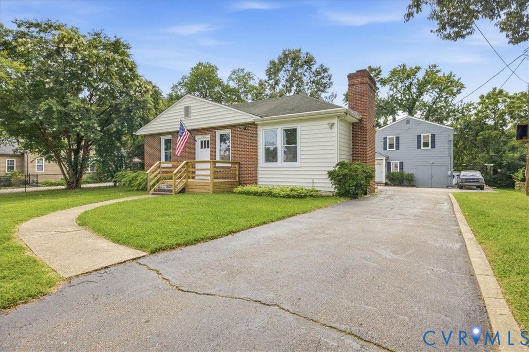 7232 Hopkins Road, North Chesterfield, VA 23237 Brick and siding exterior with a prominent brick chimney, featuring a front porch with wood railing and steps, a paved driveway, and a concrete pathway