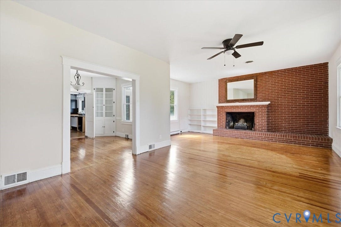 7232 Hopkins Road, North Chesterfield, VA 23237 Hardwood flooring, brick fireplace with mantel, built-in shelving, ceiling fan, and cased opening