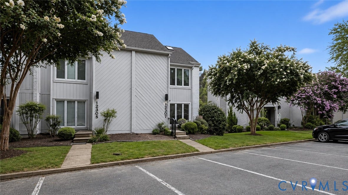 White multi-level building with vertical and diagonal siding, dark roof, and light trim