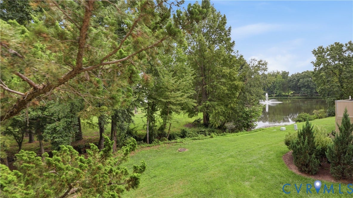 Expansive green lawn with mature trees and a tranquil pond featuring a fountain