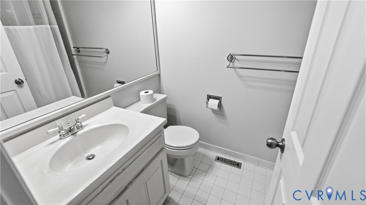 Bathroom featuring a vanity with an integrated sink, polished chrome faucet, wall-mounted mirror, and white square tile flooring