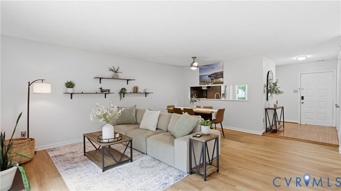 Open-concept living area with wood-finish flooring, recessed lighting, and a white paneled entry door