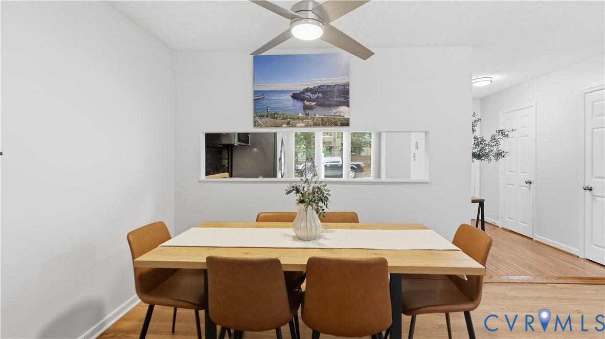 Dining area featuring a wood-finish table, white walls, and a ceiling fan with integrated lighting