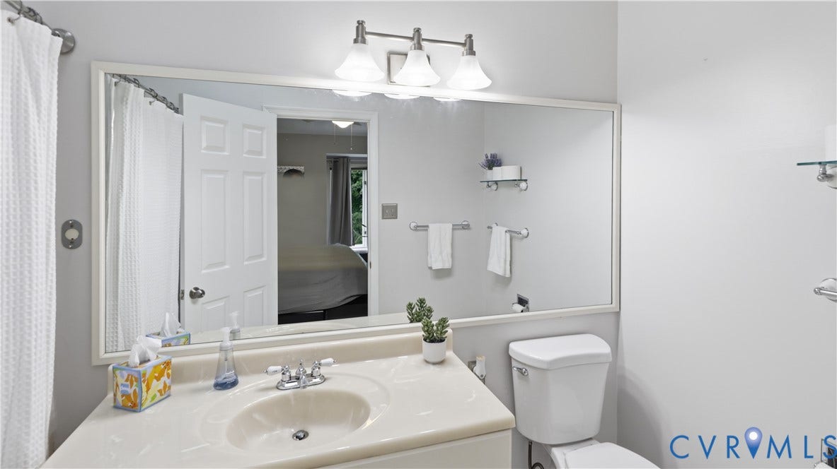 Light-toned vanity with integrated sink, chrome-finish faucet, and an expansive wall-mounted mirror