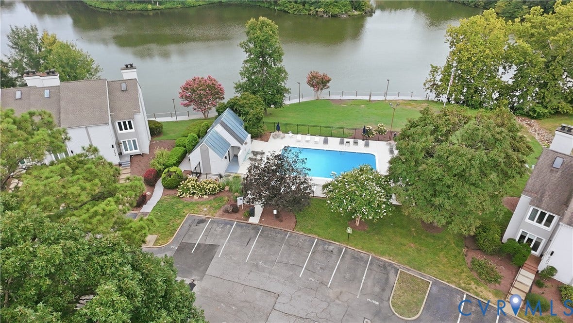 Community swimming pool with a surrounding patio, waterfront access, and manicured green spaces