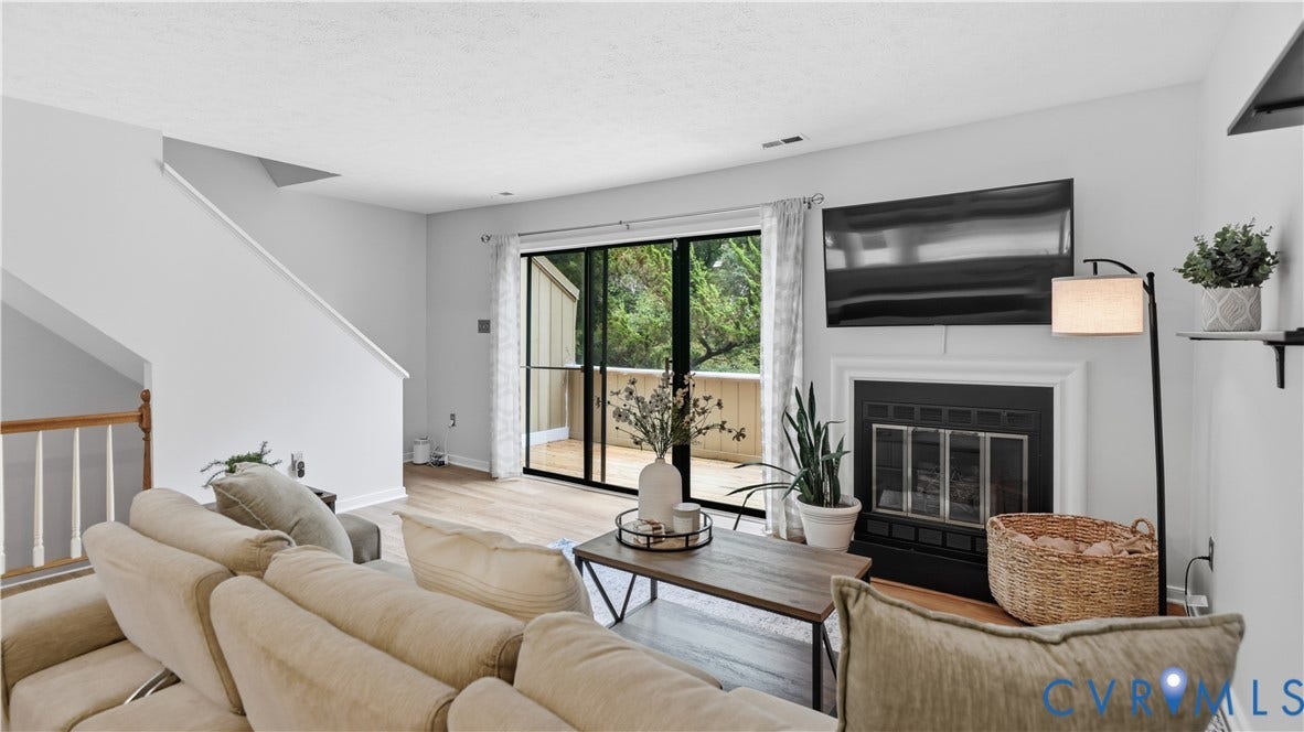 Wood-finish flooring with a fireplace featuring a black insert and white mantel