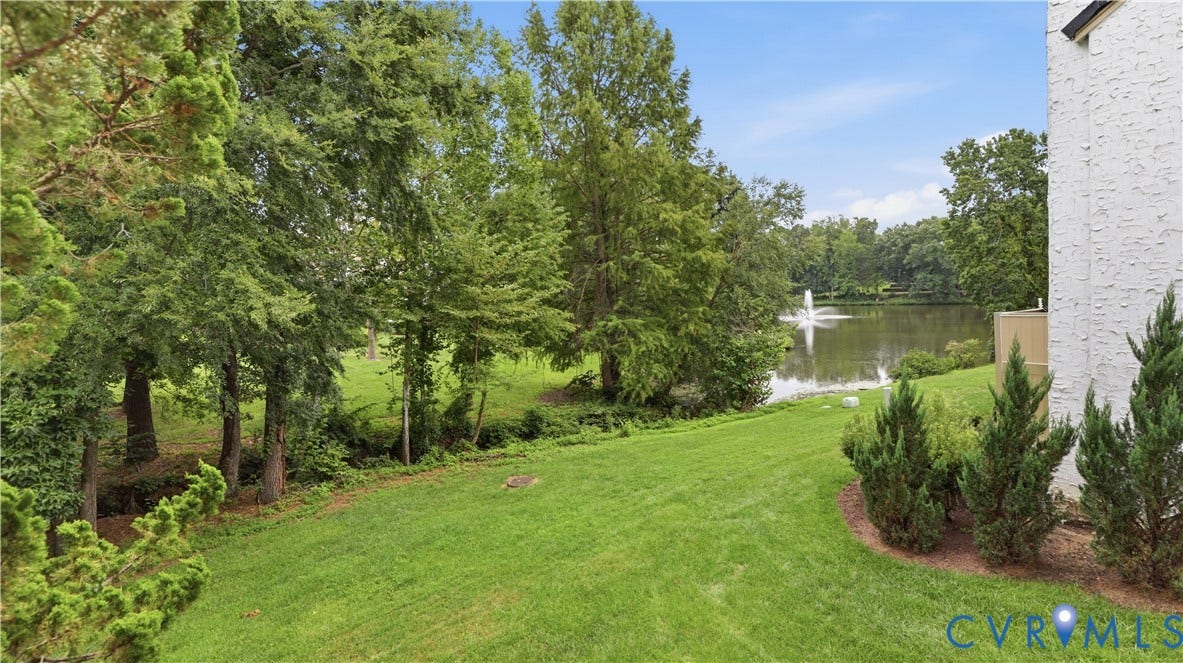 Manicured lawn with established landscaping, mature trees, and waterfront access with a fountain feature