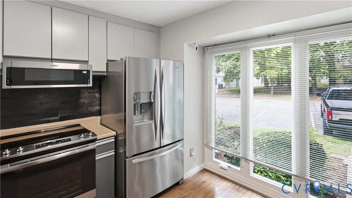 Contemporary kitchen featuring stainless steel appliances, light-toned cabinetry, and wood-finish flooring