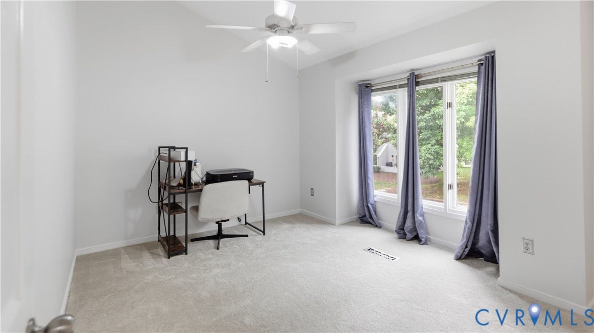 Vaulted ceiling with a ceiling fan, three large window panes, and light-toned carpeting