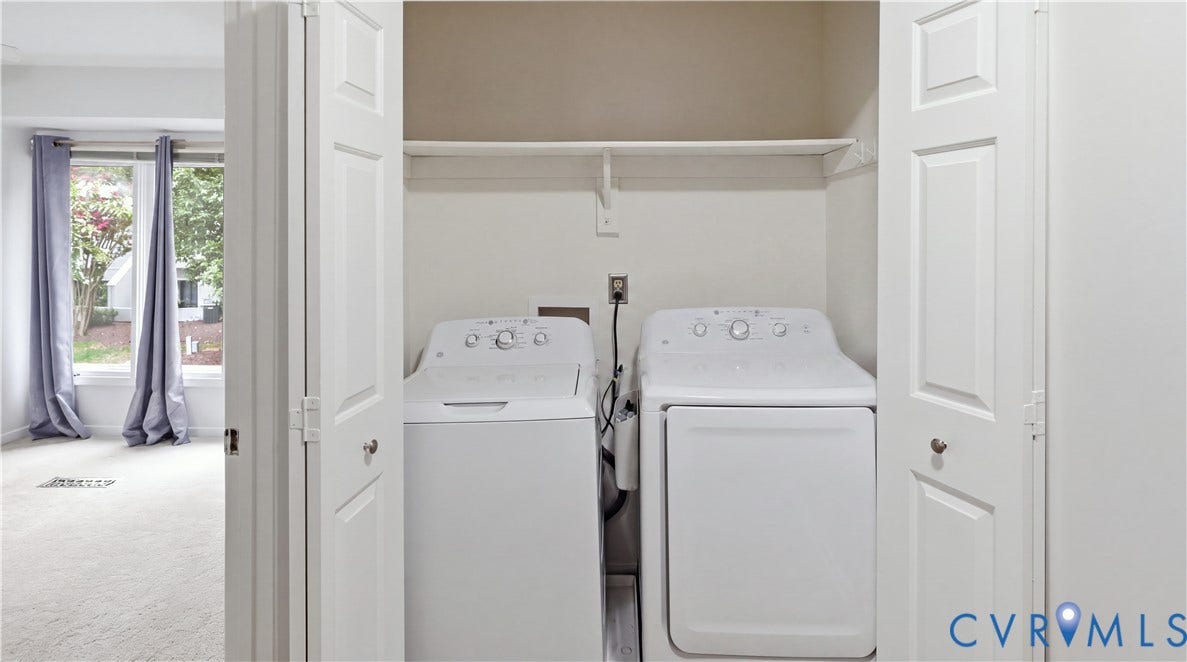 Laundry closet with a white washer and dryer, bifold doors, and an overhead storage shelf