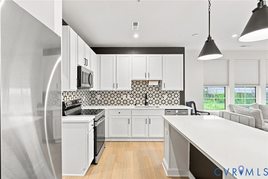 2445 Ownby Lane, #B15, Greater Scott's Addition, Richmond, VA 23220 Kitchen featuring stainless steel appliances, white cabinetry, pattern tile backsplash, and light wood-finish flooring