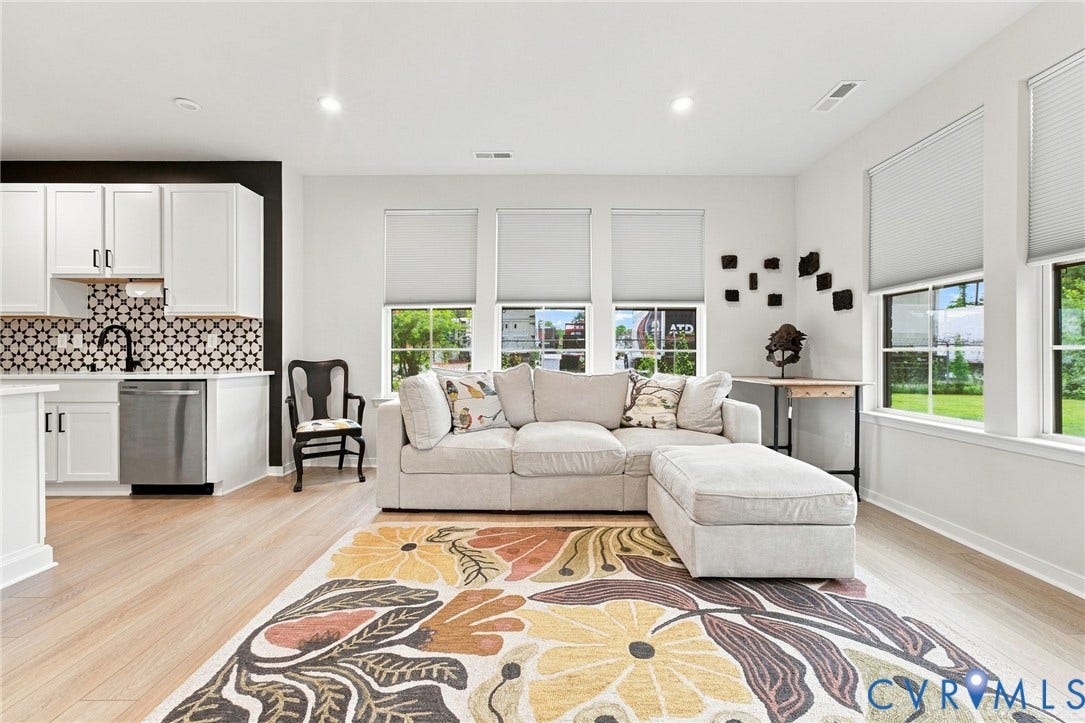 2445 Ownby Lane, #B15, Greater Scott's Addition, Richmond, VA 23220 Light wood-finish flooring throughout, white upper and lower cabinetry, stainless steel dishwasher, black and white patterned tile backsplash, and multiple windows with roller shades
