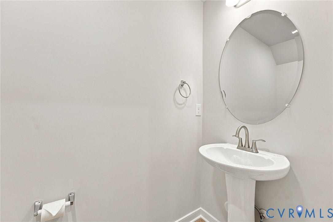 2445 Ownby Lane, #B15, Greater Scott's Addition, Richmond, VA 23220 Pedestal sink with a brushed nickel faucet, oval wall mirror, and neutral wall tones