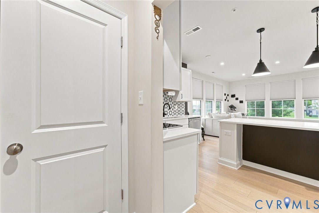 2445 Ownby Lane, #B15, Greater Scott's Addition, Richmond, VA 23220 Open-concept living space featuring wood-finish flooring, white cabinetry, a patterned tile backsplash, and recessed lighting