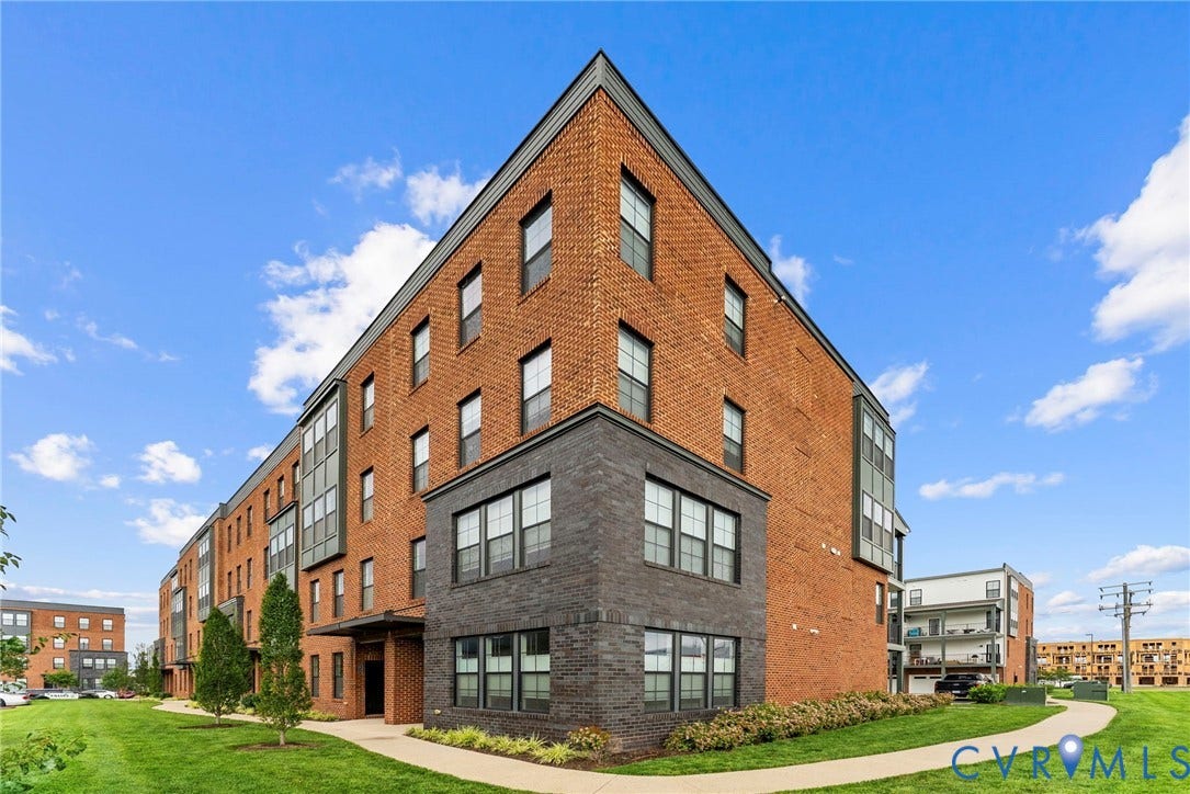 2445 Ownby Lane, #B15, Greater Scott's Addition, Richmond, VA 23220 Four-story building featuring brick and dark-toned stone cladding, multiple windows, and a paved walkway