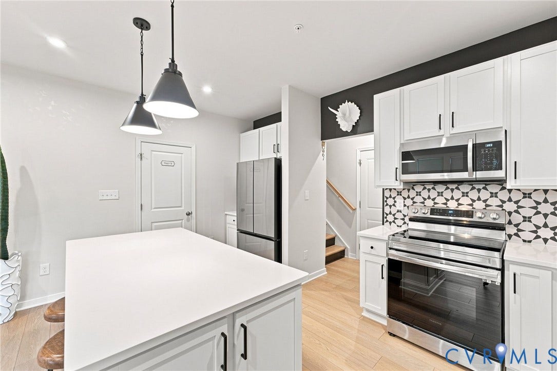 2445 Ownby Lane, #B15, Greater Scott's Addition, Richmond, VA 23220 Kitchen featuring a center island, white cabinetry, integrated stainless steel appliances, patterned backsplash, and light wood-finish flooring