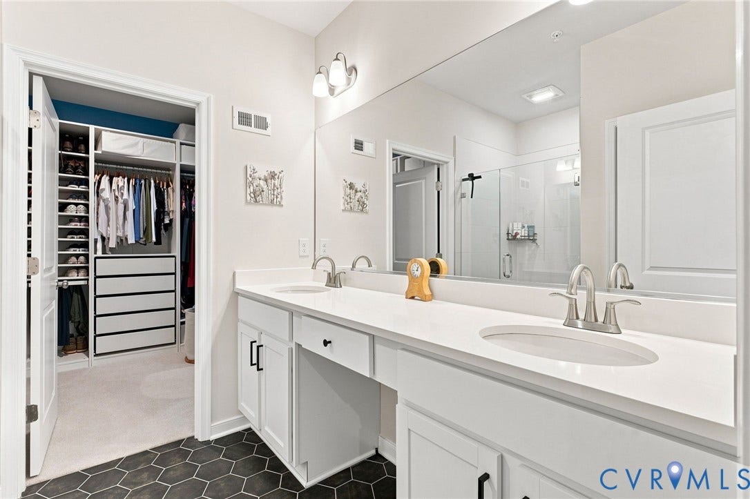 2445 Ownby Lane, #B15, Greater Scott's Addition, Richmond, VA 23220 Dual vanity with a stone finish countertop, integrated sinks, brushed nickel fixtures, and a glass-enclosed shower