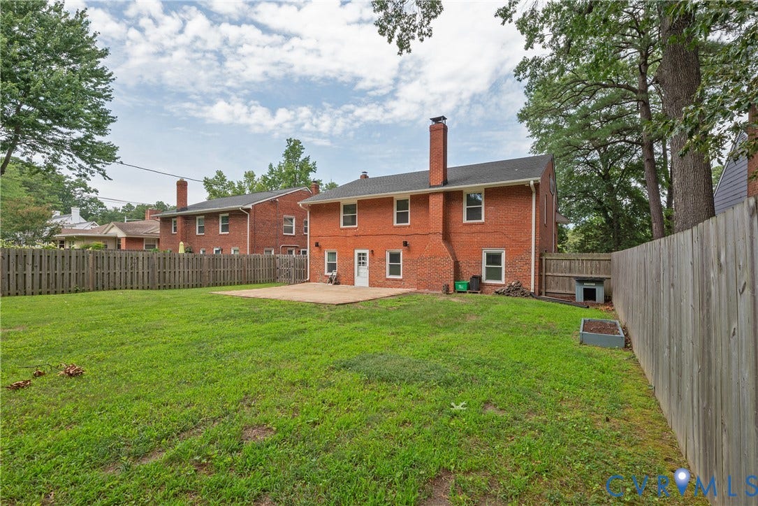 5709 Monument Avenue, Richmond, VA 23226 yard - Expansive green lawn with a concrete patio, brick exterior, and a tall wood fence