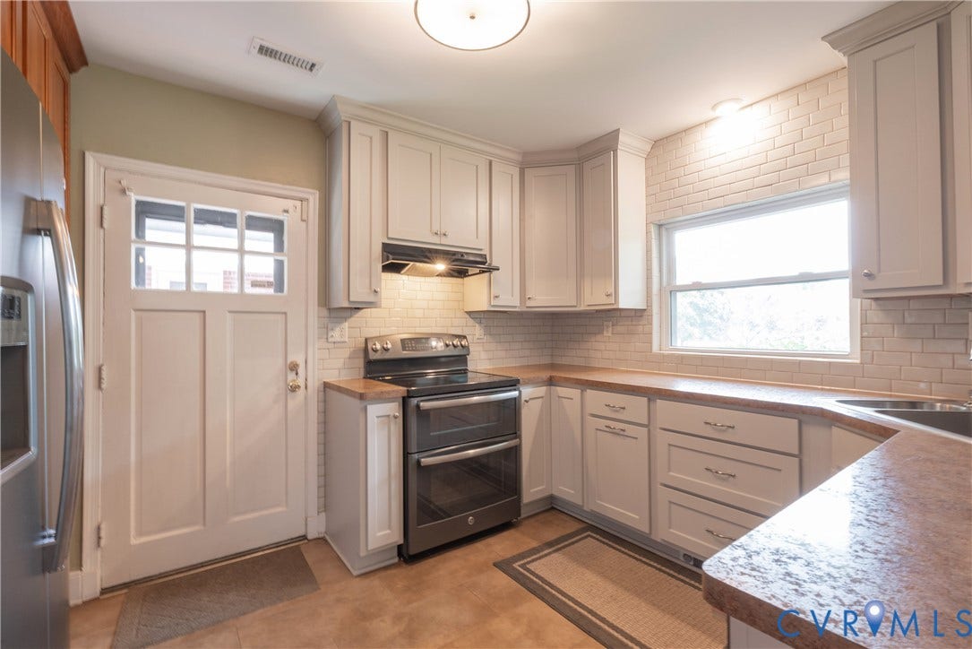 5709 Monument Avenue, Richmond, VA 23226 Kitchen with shaker-style cabinetry, subway tile backsplash, integrated stainless steel appliances, durable countertop, and transom-style door
