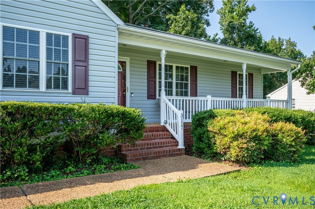 3117 Pinefields Drive, Henrico, VA 23231 Charming farmhouse-style residence featuring light blue horizontal siding, brick foundation, and a welcoming front porch with white railings and columns