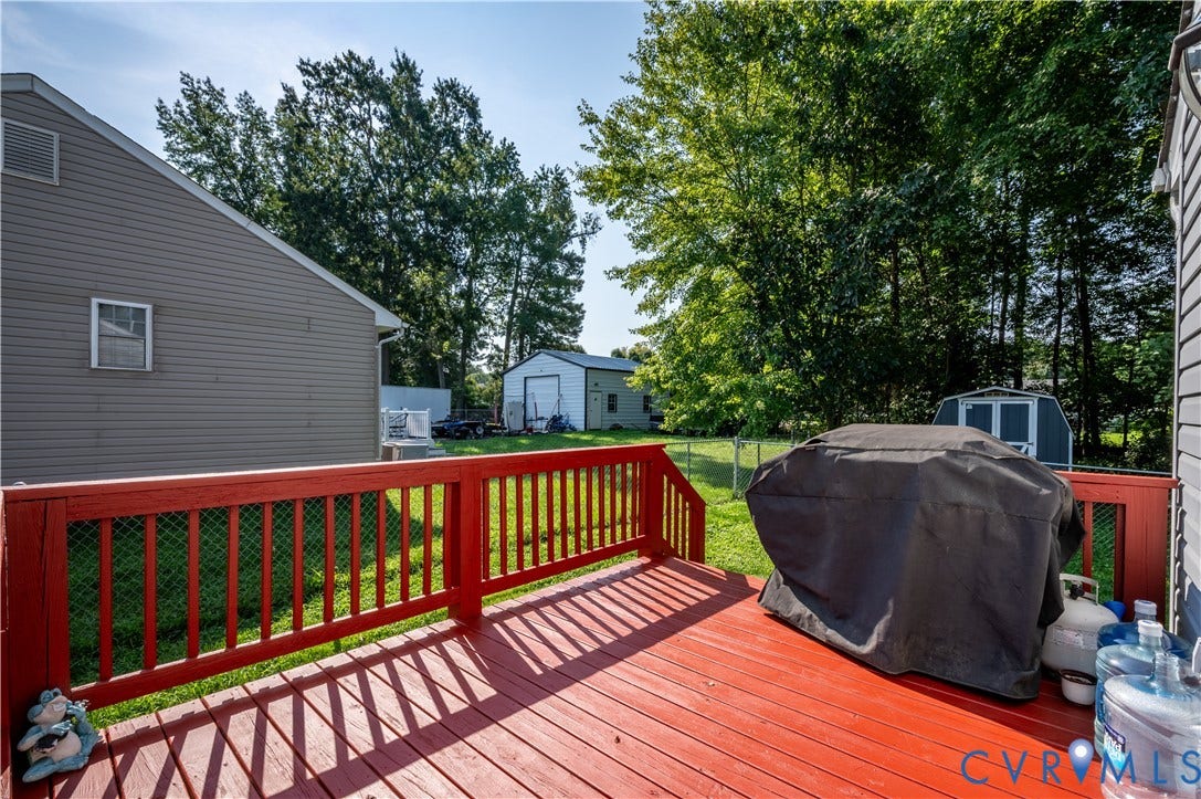 3117 Pinefields Drive, Henrico, VA 23231 Expansive red-stained deck with baluster railing, leading to a fenced yard with mature trees