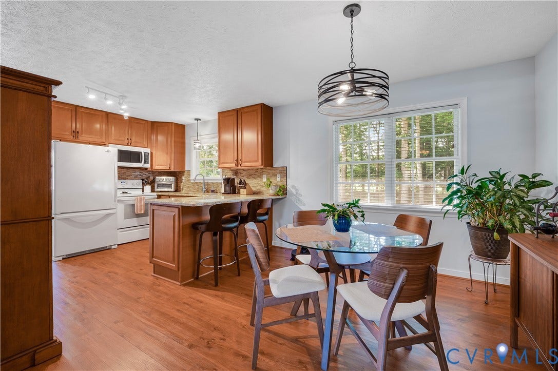 3117 Pinefields Drive, Henrico, VA 23231 Kitchen and dining area featuring wood-finish flooring, wood cabinetry, granite countertops, and a window with natural light