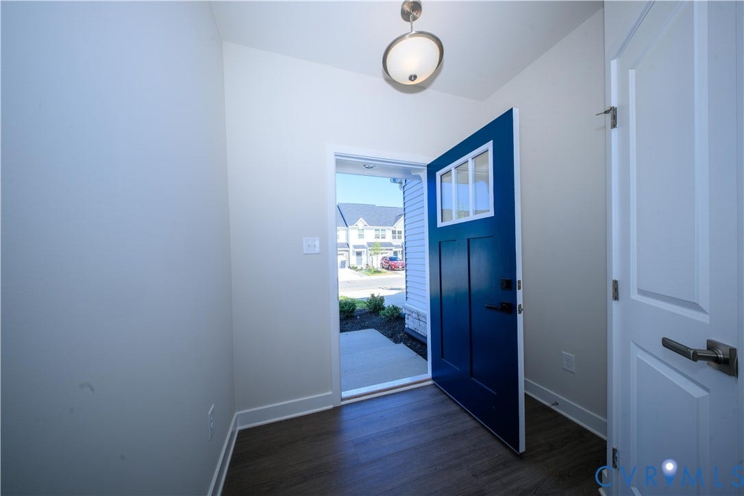 Bright entry hall with wood-finish flooring, a contemporary semi-flush mount light fixture, and a bold blue door featuring transom windows