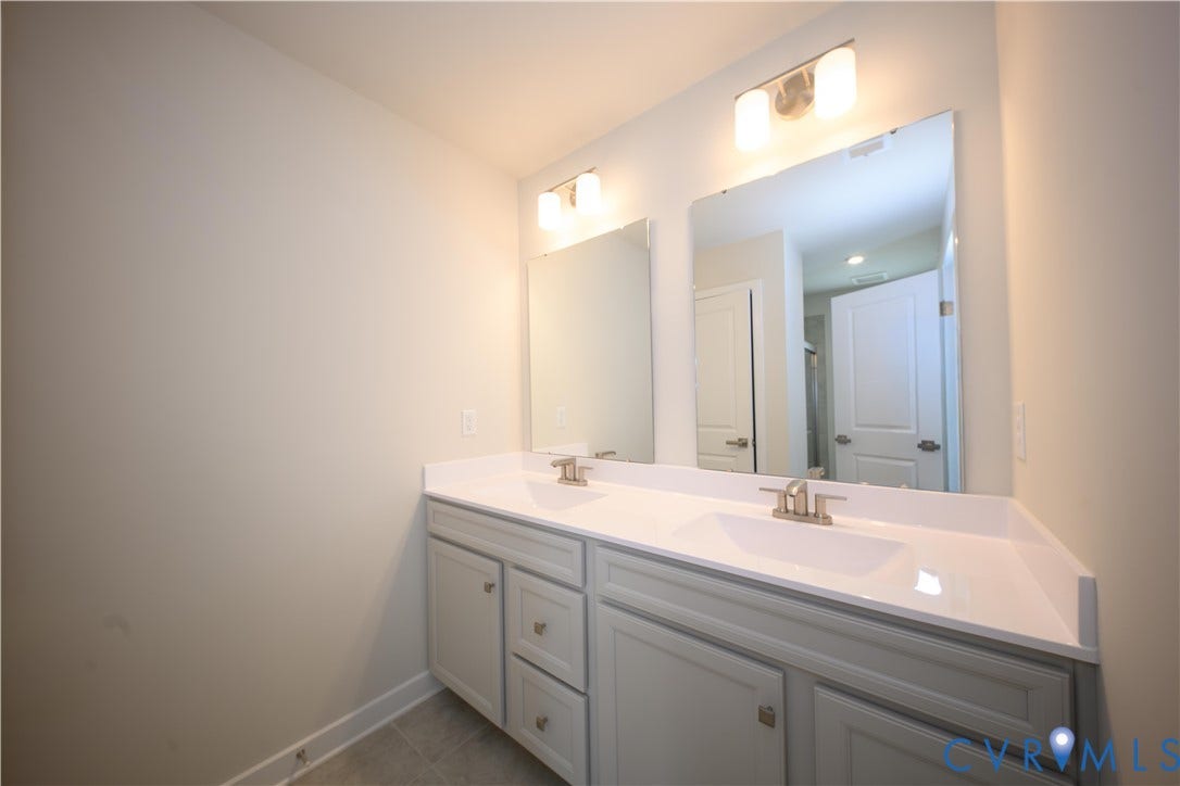 Dual vanity with white countertops, undermount sinks, brushed nickel faucets, and coordinating wall-mounted light fixtures
