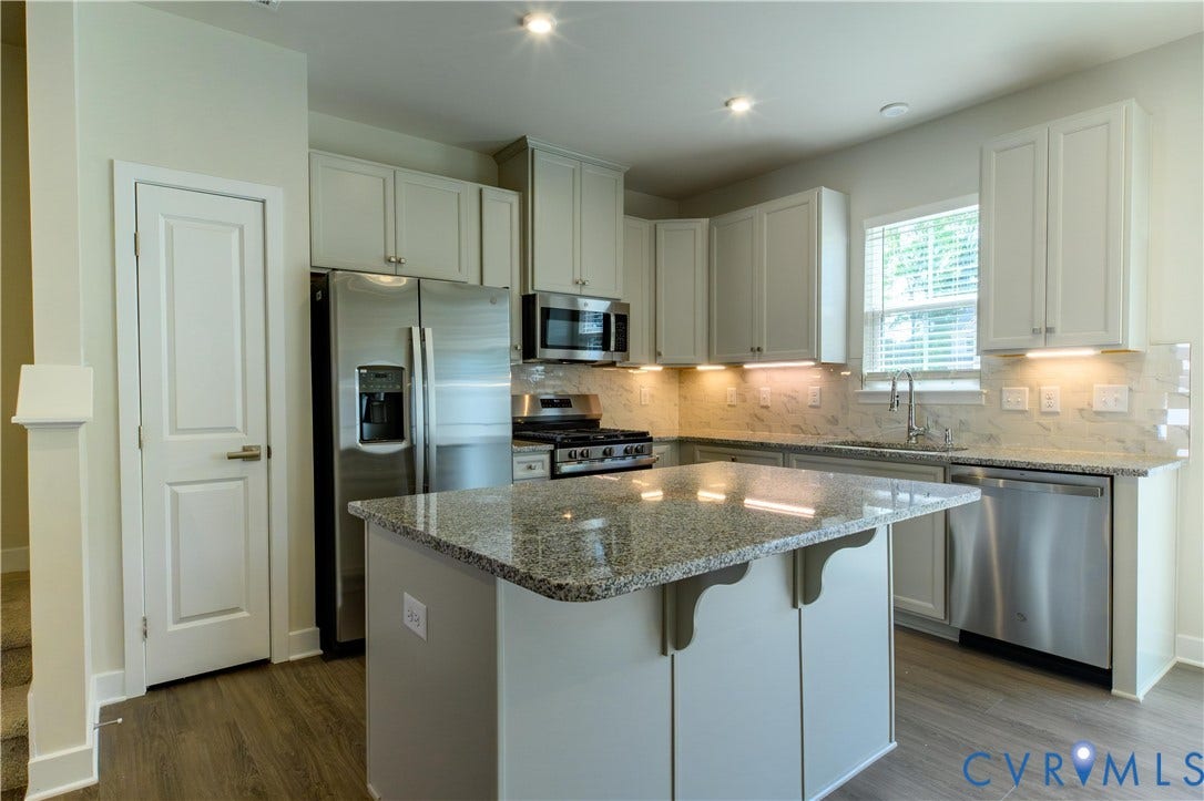 Kitchen featuring light-finish cabinetry, granite countertops, stainless steel appliances, and a central island