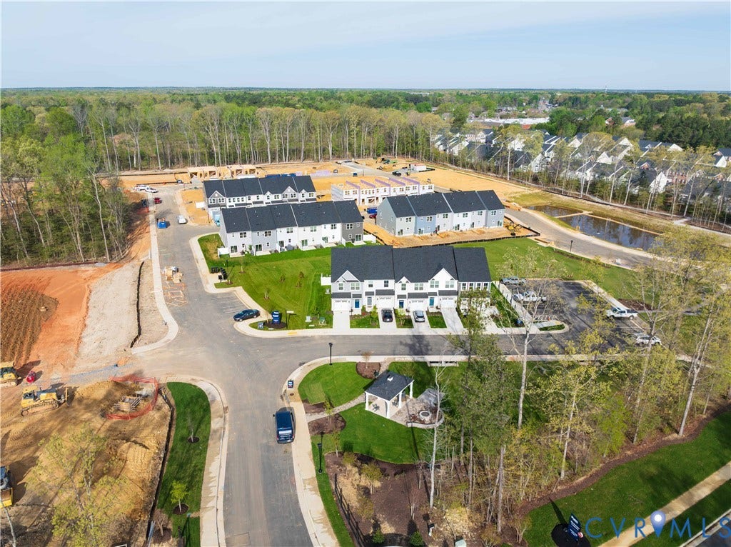 Developed community featuring townhomes with attached garages, paved driveways, and green lawns