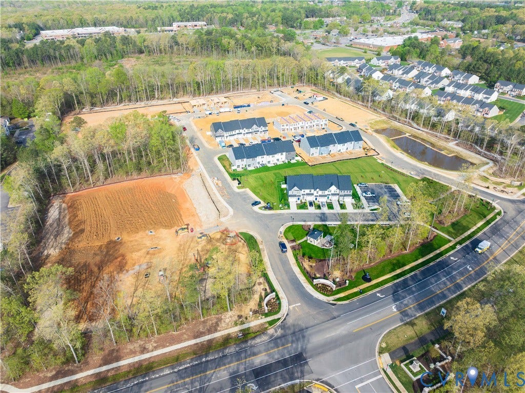 New construction community with multiple phases, featuring established landscaping, paved roadways, and an on-site retention pond