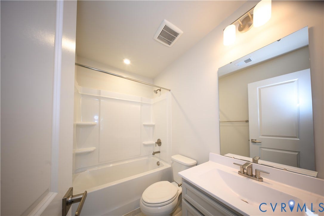 White shower-over-tub combination with integrated shelving, brushed nickel fixtures, and a sleek vanity with an undermount sink