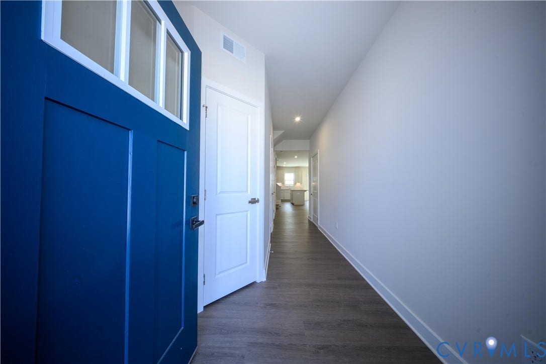 Blue entry door with transom windows, wood-finish flooring, recessed lighting, and crisp white walls