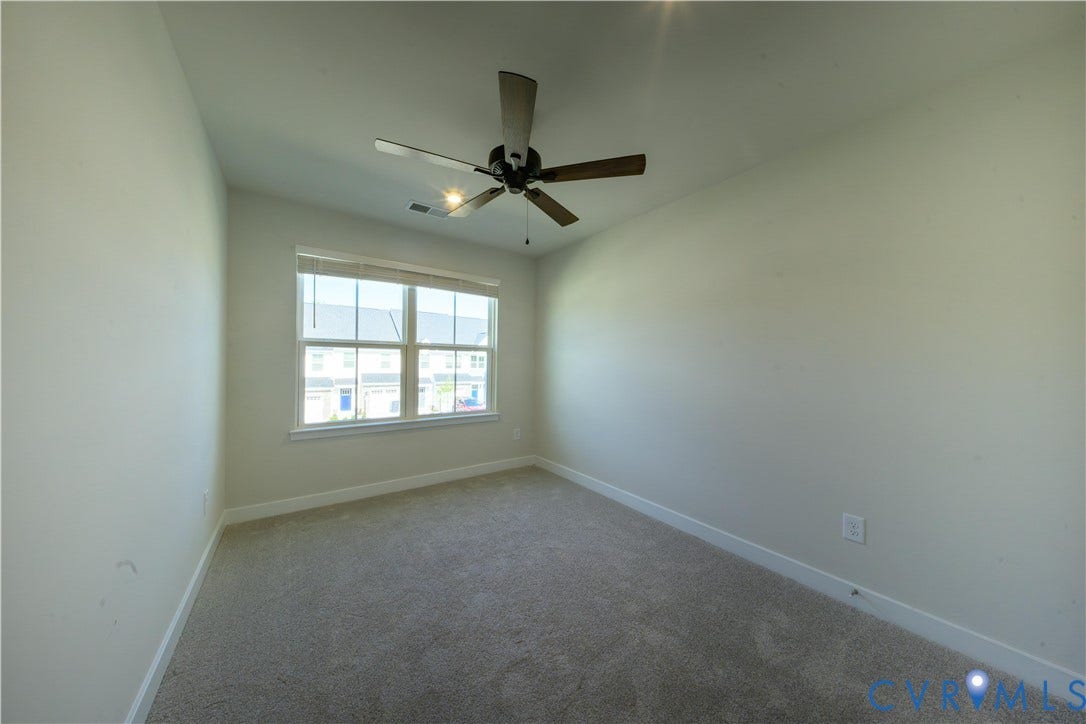 Neutral-toned carpeting, white walls, and a multi-pane window with blinds