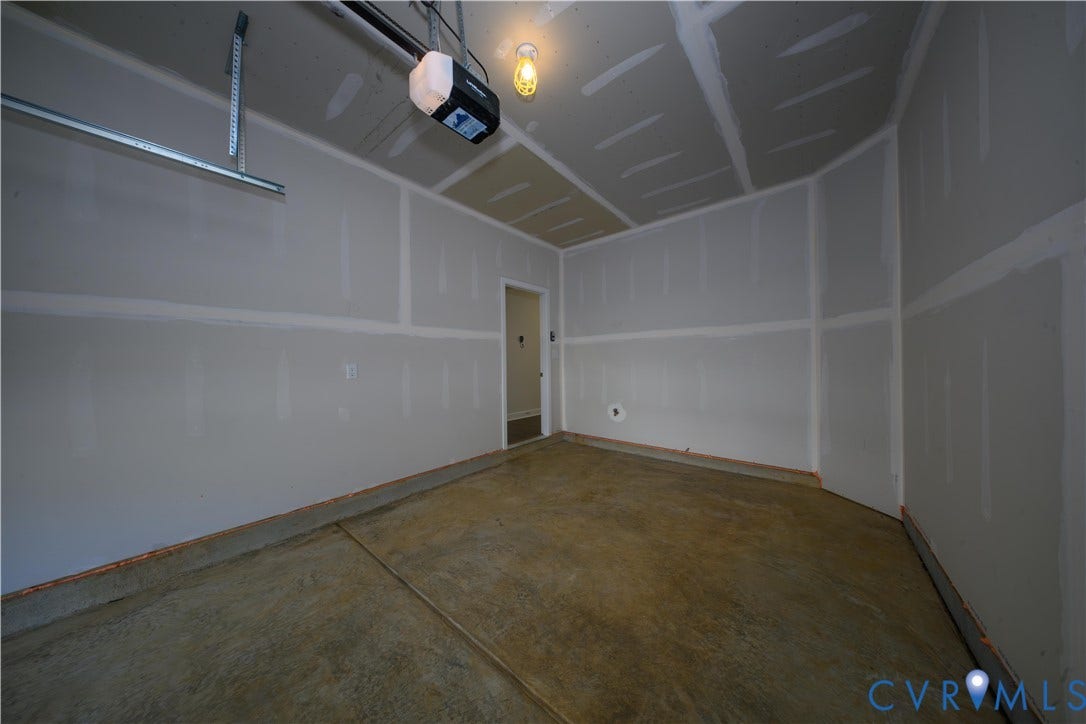 Attached garage with concrete flooring, drywall walls, and an automatic garage door opener