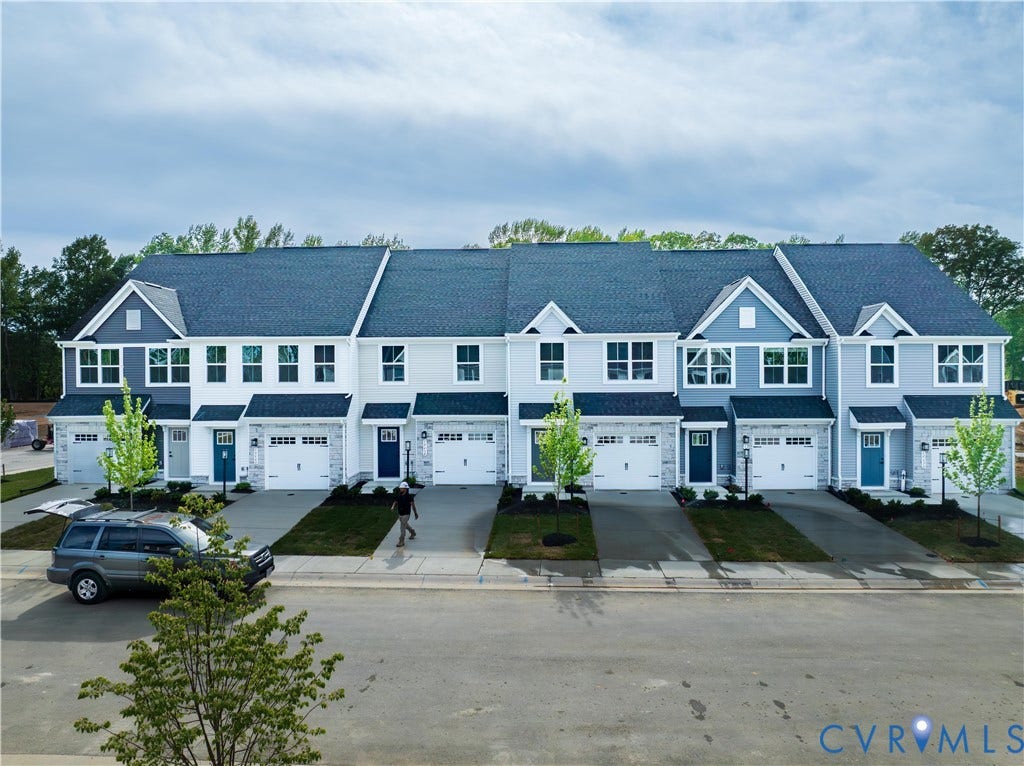 Contemporary townhomes featuring integrated garages, distinct front doors, and uniform dark roofing