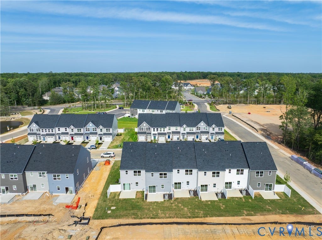 Newly constructed townhome community with modern exterior finishes, private patios, and lush surrounding greenery