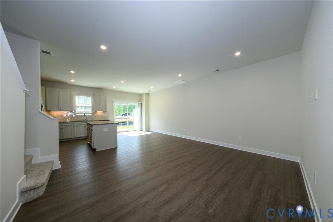 Open-concept living area with wood-finish flooring, recessed lighting, and sliding glass door