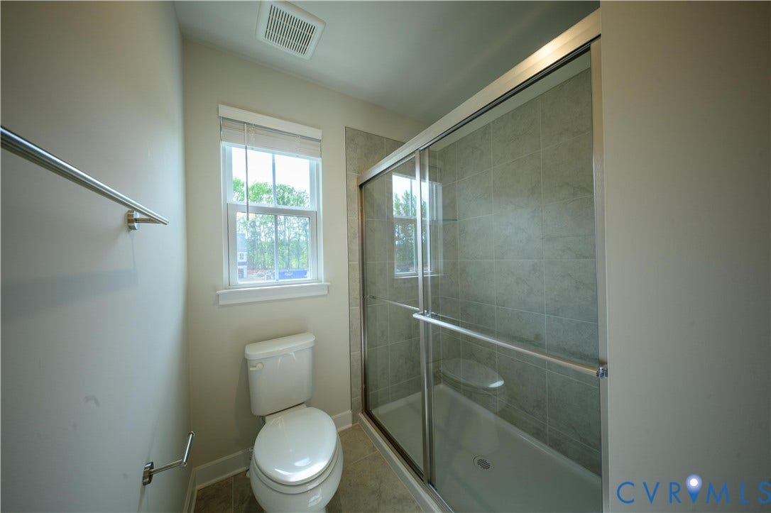 Shower with sliding glass enclosure, tiled surround, and integrated shower seat
